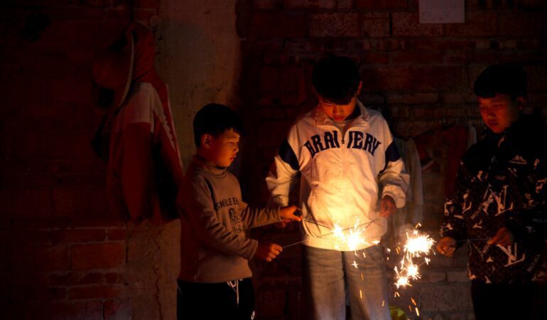Hani village boys lighting firecrackers while exploring the Yuanyang rice terraces during Spring Festival